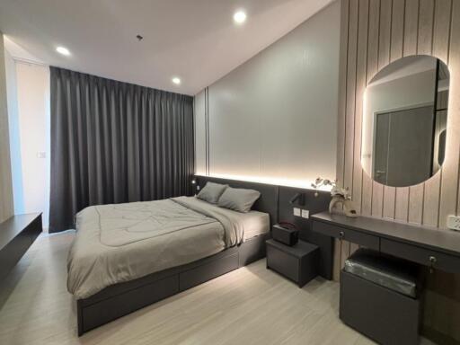 Modern bedroom with double bed, nightstands, and a vanity under warm lighting.