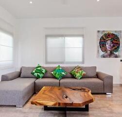 Modern living room with a sectional sofa, wooden coffee table, and artwork on the wall