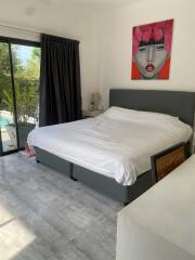 Modern bedroom with large bed, artwork on the wall, and patio access