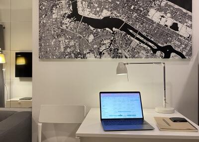 Home office setup with map artwork, laptop on desk, and modern furniture