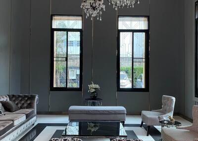 Elegant living room with chandeliers, large windows, modern furniture, and decorative elements
