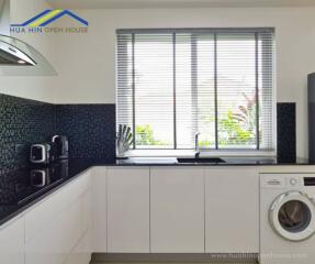 Modern kitchen with window, black countertops, white cabinets, and appliances