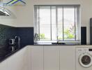 Modern kitchen with window, black countertops, white cabinets, and appliances