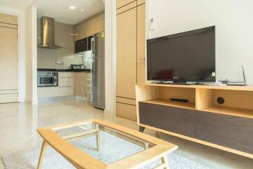 Modern living room with kitchen area, TV, and coffee table