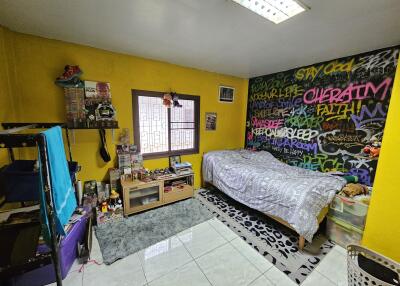 Colorful bedroom with graffiti wall, single bed, and window