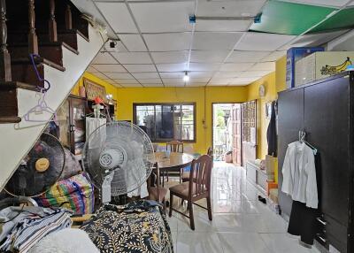 Spacious room with dining area, stairwell, and various household items, featuring a window and door for natural light.