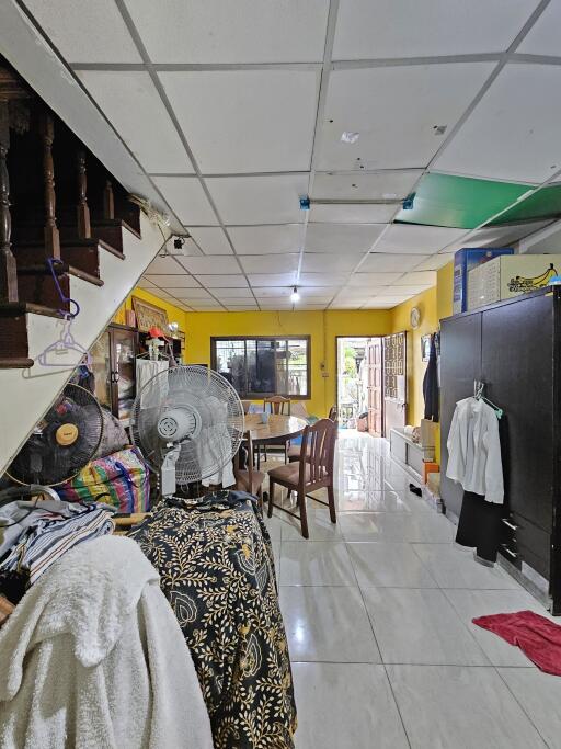 Spacious room with dining area, stairwell, and various household items, featuring a window and door for natural light.