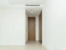 Minimalist hallway with white walls and a wooden door