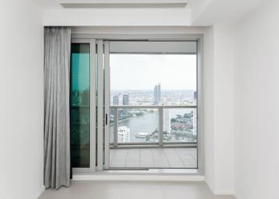 A modern living room with a large glass sliding door leading to a balcony with a city view.