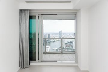 A modern living room with a large glass sliding door leading to a balcony with a city view.