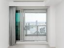 A modern living room with a large glass sliding door leading to a balcony with a city view.