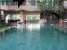 Outdoor swimming pool area with modern building and surrounding greenery