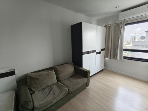 Modern bedroom with a beige sofa, white wardrobe, and large window