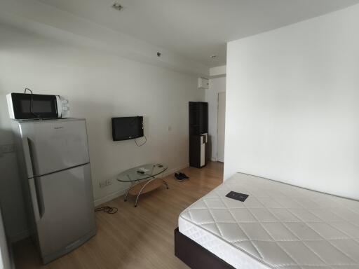 Studio apartment with bed, appliances, and small table