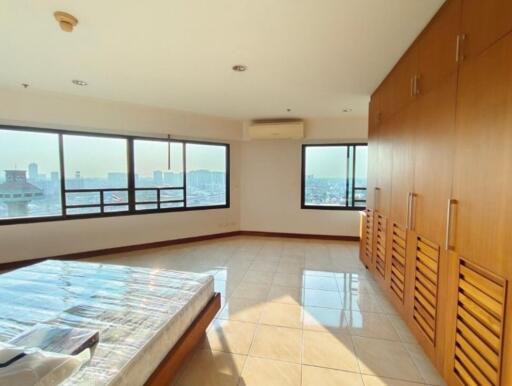 Spacious bedroom with large windows and built-in wooden wardrobes