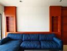 Modern living room with blue sectional sofa and built-in wooden shelves