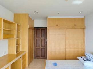 Spacious bedroom with built-in wooden shelves and closets