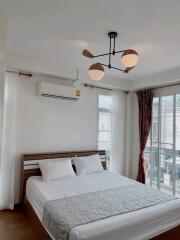 A bedroom with a large window, bed, and modern lighting