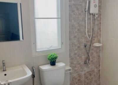 A bathroom with a sink, toilet, shower area, and window.