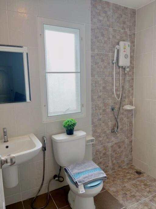 A bathroom with a sink, toilet, shower area, and window.