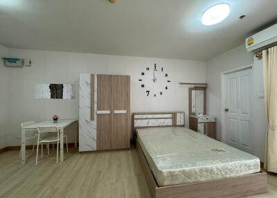 Modern bedroom with minimalist decor including a bed, wardrobe, desk, and wall clock