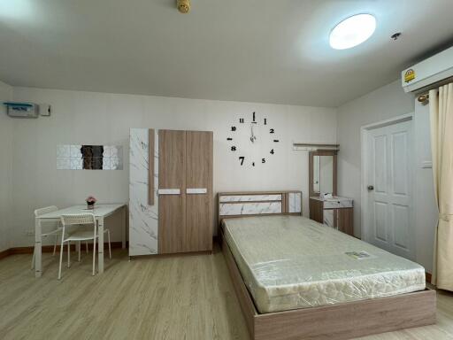 Modern bedroom with minimalist decor including a bed, wardrobe, desk, and wall clock