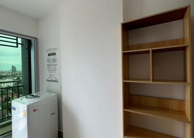 Utility room with a washing machine, wooden shelves, and window offering city view