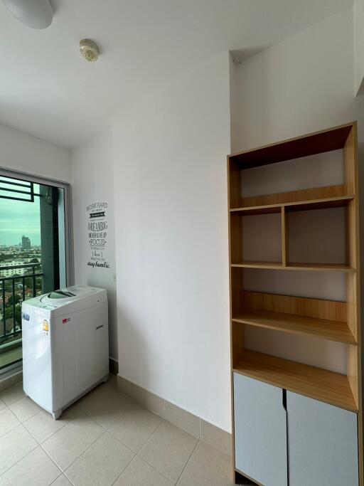 Utility room with a washing machine, wooden shelves, and window offering city view