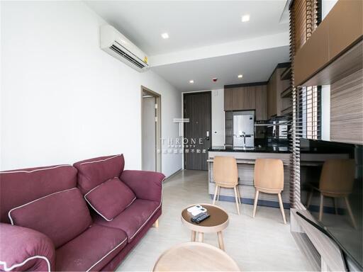 Modern living room with open kitchen and purple sofa