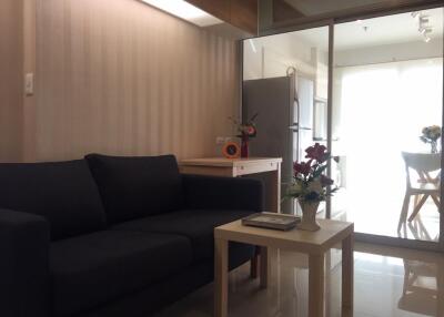 Living room with dark blue sofa, coffee table, and view into kitchen