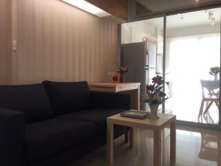 Living room with dark blue sofa, coffee table, and view into kitchen