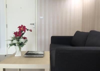 Modern living room with black sofa, flowers on the table, and white door