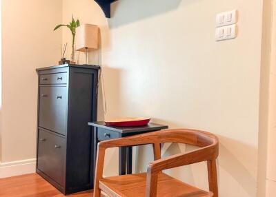 Entrance area with a wooden chair, small table, cabinet, and wall-mounted shelf with hooks