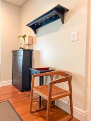 Entrance area with a wooden chair, small table, cabinet, and wall-mounted shelf with hooks