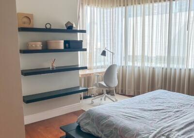 Modern bedroom with large windows, floating shelves, and a study desk