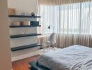 Modern bedroom with large windows, floating shelves, and a study desk