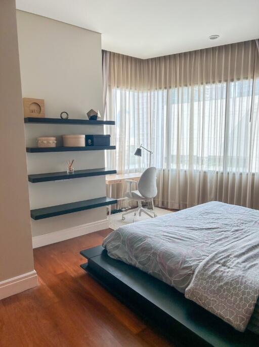 Modern bedroom with large windows, floating shelves, and a study desk