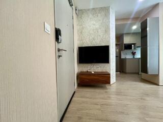 Modern living room with wall-mounted TV and kitchen in the background