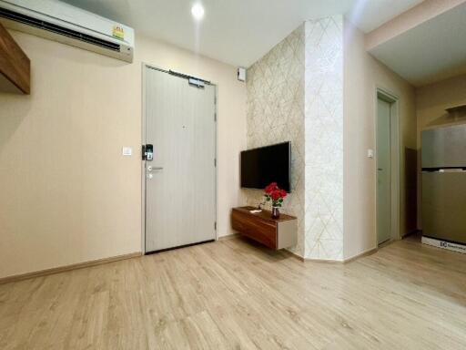 Modern living room with wooden flooring, wall-mounted TV, air conditioning unit, and decorative wall