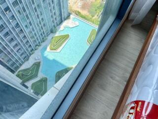 View from a high-rise apartment showing a swimming pool with unique green islands below.