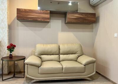 Living room with beige leather sofa and wall-mounted shelves