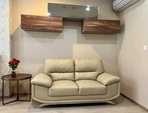 Living room with beige leather sofa and wall-mounted shelves