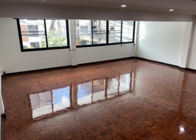 Spacious living room with large windows and polished hardwood floors