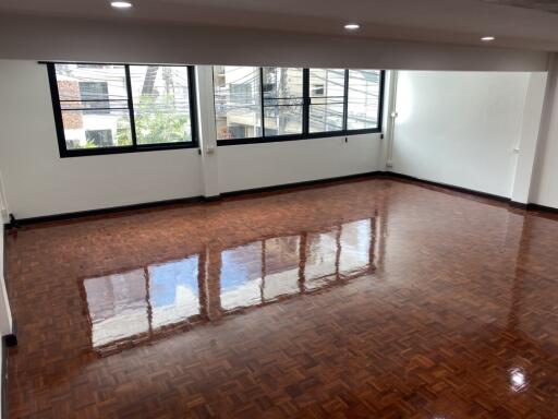 Spacious living room with large windows and polished hardwood floors