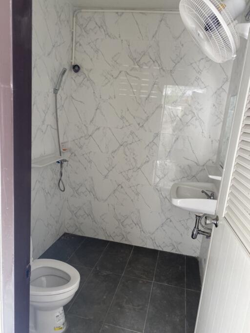 Clean bathroom with marble walls and black tile floor