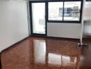 Empty bedroom with parquet flooring and large window