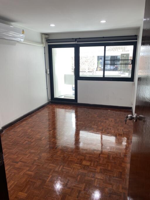 Empty bedroom with parquet flooring and large window