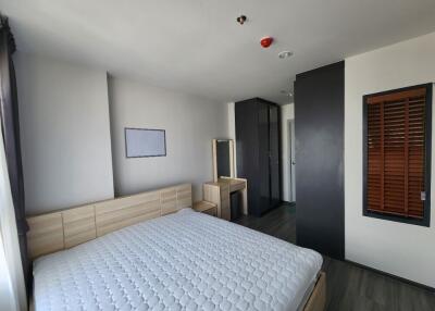 Modern bedroom with minimalist design featuring a large bed, wooden accents, and a small desk