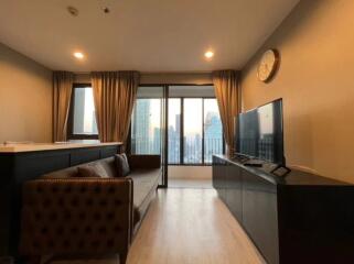 Modern living room with a sofa, TV, and large windows.