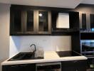 Modern kitchen with dark cabinets, appliances, and white countertop